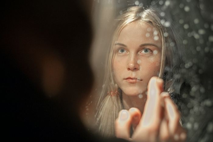 Une femme qui se regarde dans un miroir, pensive